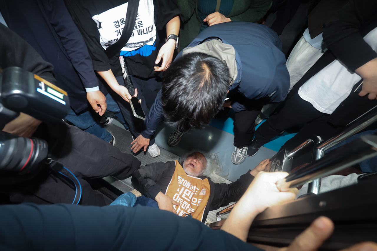 박경석 전국장애인차별철폐연대(전장연) 대표가 21일 서울 지하철 4호선 혜화역에서 제62차 ‘출근길 지하철 탑니다’ 시위를 벌이던 중 이를 저지하던 서울교통공사 관계자와 충돌하며 넘어져 있다.   [연합]