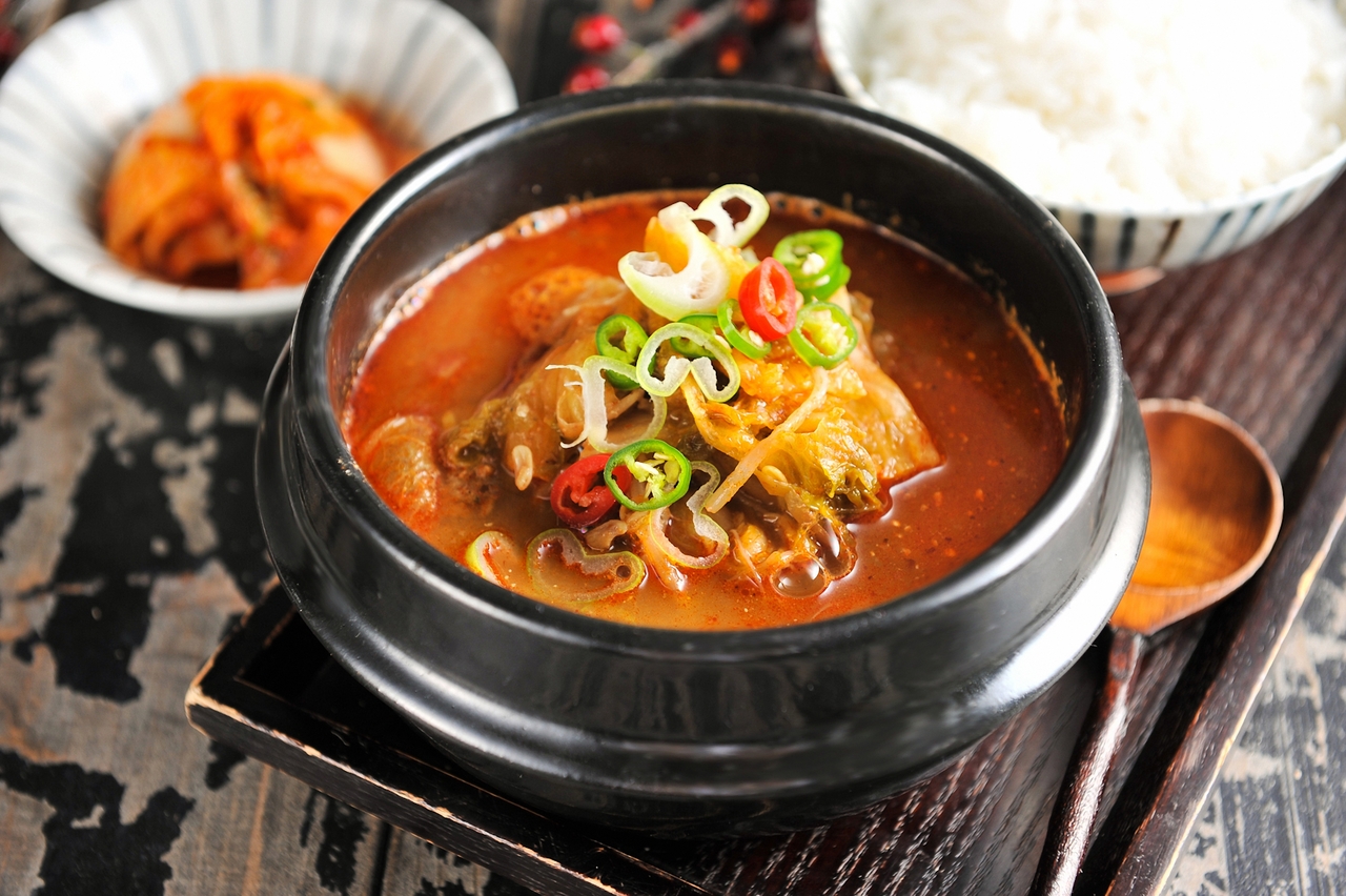 Steaming bowl of Korean haejangguk hangover soup with vegetables and meat in a hot stone bowl