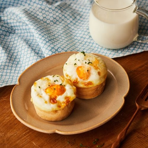 Freshly baked gyeran-ppang oval loaves with whole eggs baked in, styled on a wooden board for a Korea Herald winter street food feature