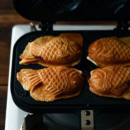 Golden fish shaped bungeoppang Korean winter street pastry with sweet red bean paste filling arranged in a row from a Seoul vendor cast iron mold