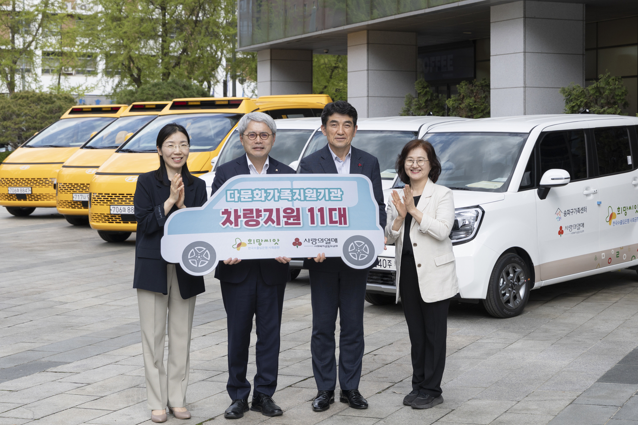 Eximbank CEO Yoon Hee-sung (center left) and Community Chest of Korea Secretary-General Hwang In-sik (center right) pose for a photo during the donation ceremony of vehicles for organizations that support multicultural families in Seoul on Monday. (Eximbank)