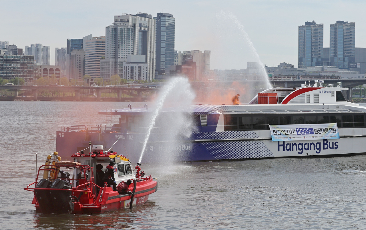 Firefighters conduct a fire drill simulating a battery compartment fire on a Hangang River Water Bus near Mapo Bridge in the Han River in Seoul on Wednesday. (Yonhap)