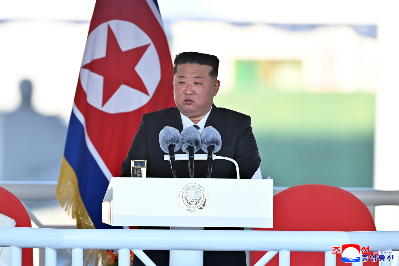 Kim delivers a nationally televised speech beside the North Korean flag, declaring the destroyer’s launch a step toward expanding naval deterrence on Friday. (Yonhap)
