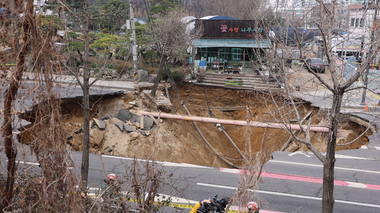 A 20-meter-wide and 18-meter-deep sinkhole, which injured one driver and swallowed a motorcyclist on March 24, is seen at an intersection in Gangdong-gu, eastern Seoul , March 25. (Yonhap)