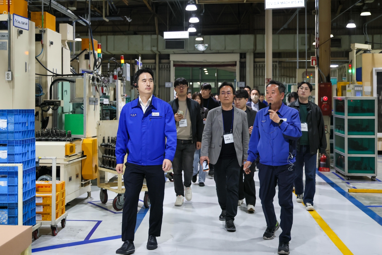 Hansae Mobility CEO Kim Ik-hwan (left) tours the company’s Daegu plant on Wednesday as part of a media tour event. (Hansae Mobility)