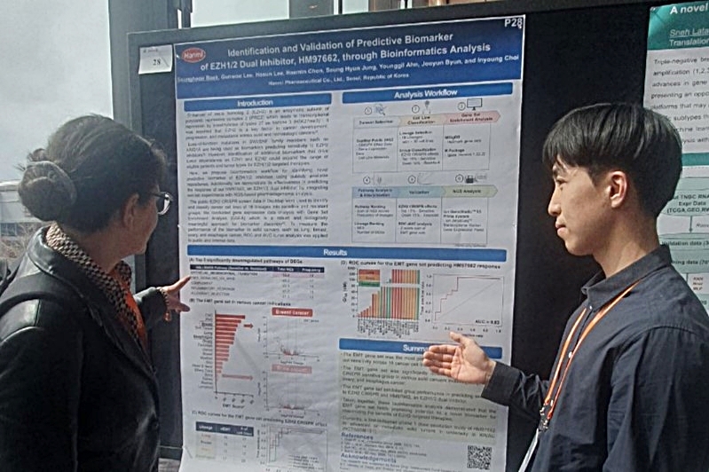 백승현 한미약품 R&D센터 연구원(오른쪽)이 4일(현지시각) 열린 ‘2025 Bio-IT World Conference & Expo’에서 차세대 항암 신약 ‘EZH1/2 이중 저해제(HM97662)’의 주요 연구 내용이 담긴 포스터를 토대로 참석자에게 설명하고 있다. [한미약품 제공]