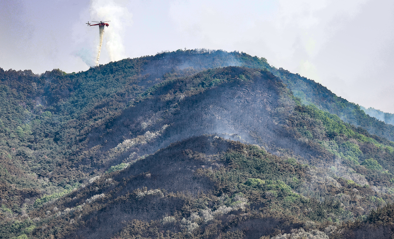 Helicopters dump water on a mountain in Daegu as a wildfire continued for a second day on Tuesday. (Yonhap)