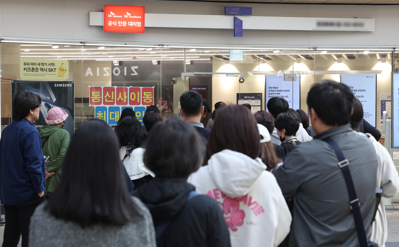 People line up outside an SK Telecom store in Seoul to exchange their universal subscriber identity module (USIM) cards on Tuesday. (Yonhap)