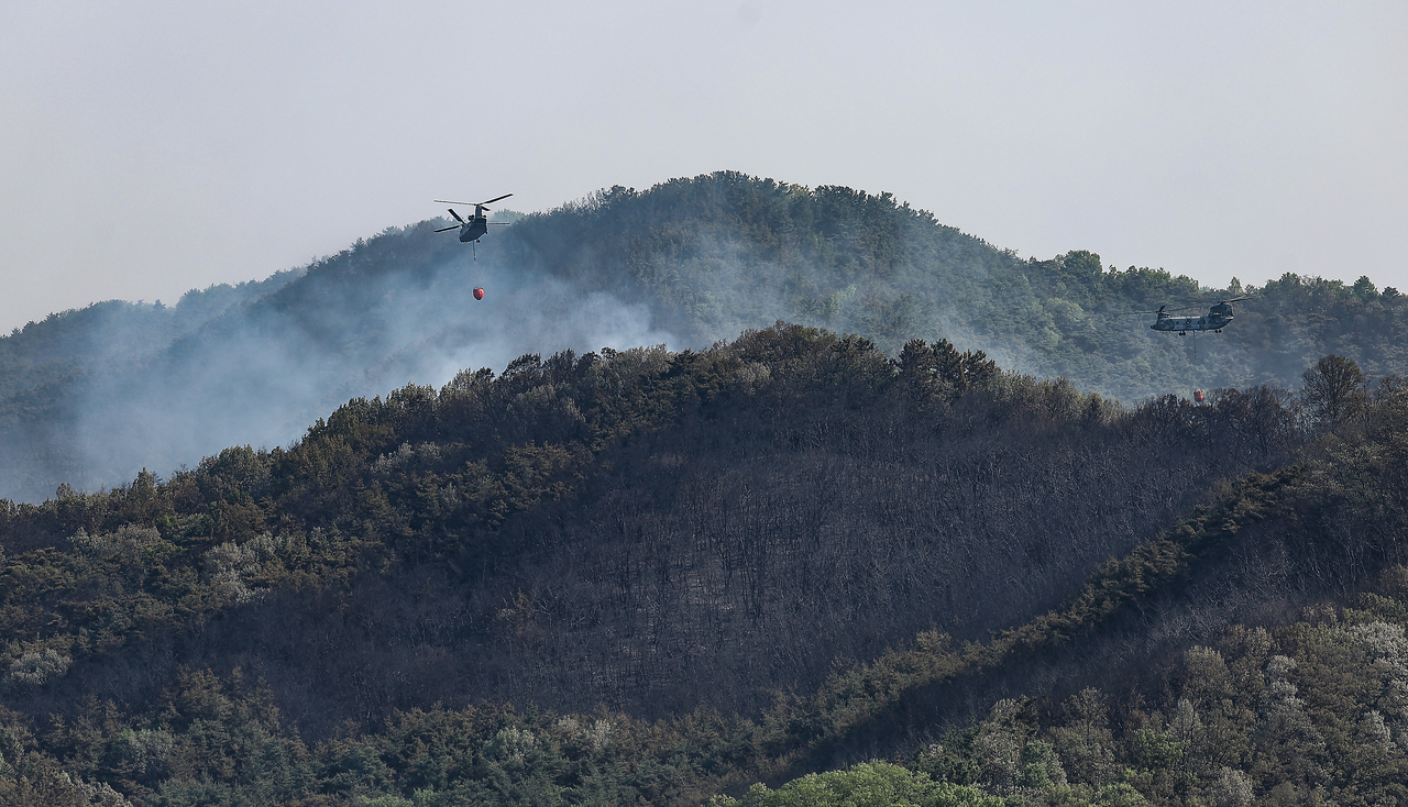 Helicopters dump water on a mountain in Daegu, some 230 kilometers southeast of Seoul, as wildfire continues for a second day on Tuesday. (Yonhap)
