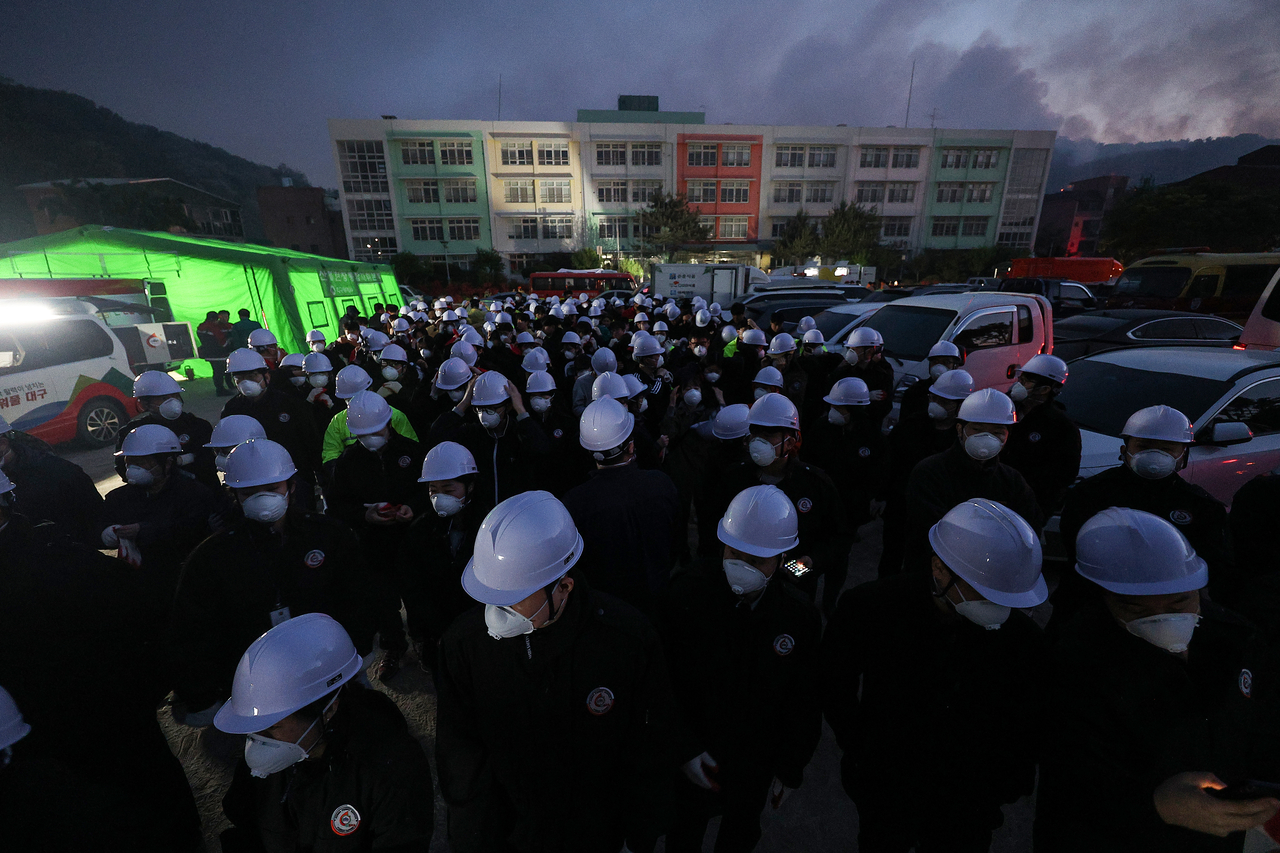 Government officials mobilized for firefighting efforts prepare for deployment at the Command Headquarters for the forest fire site, set up at Seobyeon Elementary School in Buk-gu, Daegu, as morning breaks. (Yonhap)