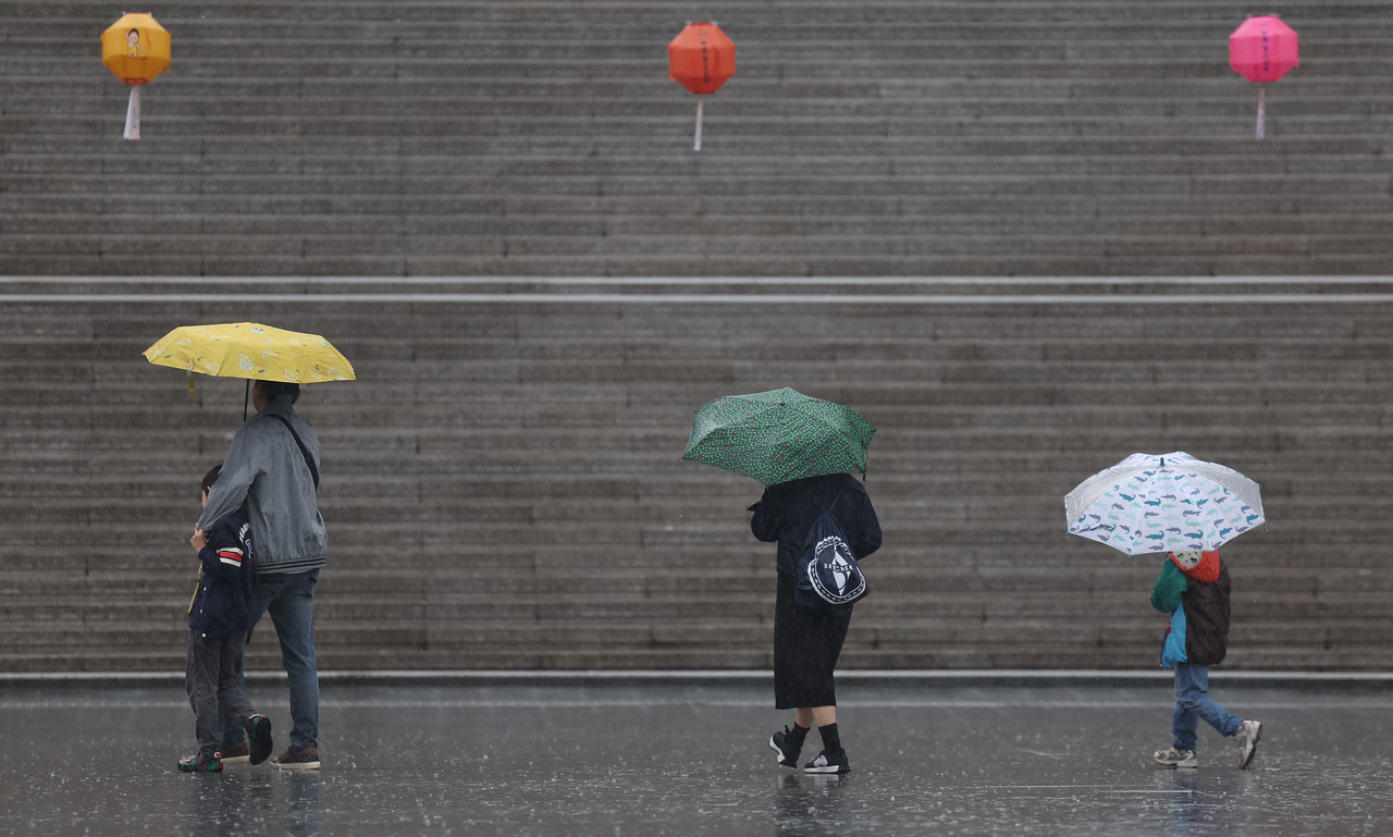 A family walks through the rain with umbrellas at Gwanghwamun Square in Jongno-gu, central Seoul on April 22. (Yonhap)