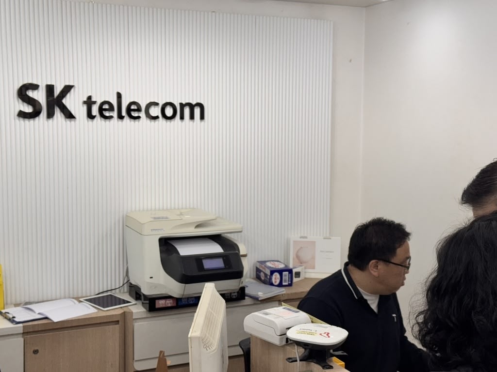 An SK Telecom employee assists customers seeking to replace their USIM cards at a retail branch in Seoul on Monday, following a security incident involving potential exposure of SIM-linked subscriber data. (Moon Joon-hyun/The Korea Herald)
