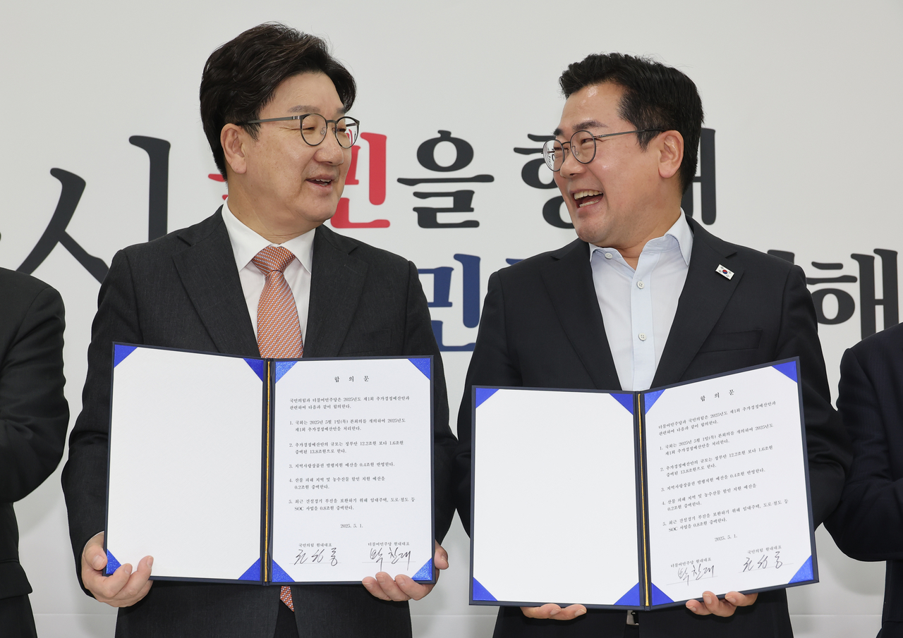 Floor Leaders Rep. Kweon Seong-dong (left) of the People Power Party and Rep. Park Chan-dae of the Democratic Party of Korea hold up their signed agreements on the extra budget at the National Assembly on Thursday. (Yonhap)