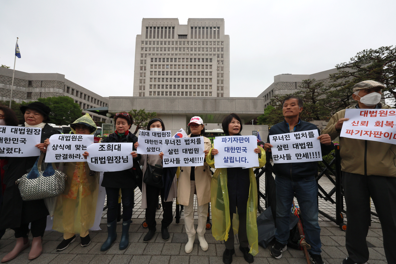 1일 서울 서초구 대법원 앞에서 보수단체 회원들이 더불어민주당 이재명 대선 후보의 공직선거법 위반 혐의 사건이 유죄 취지로 파기환송 되자 이를 반기는 피켓을 들어 보이고 있다. <연합뉴스>