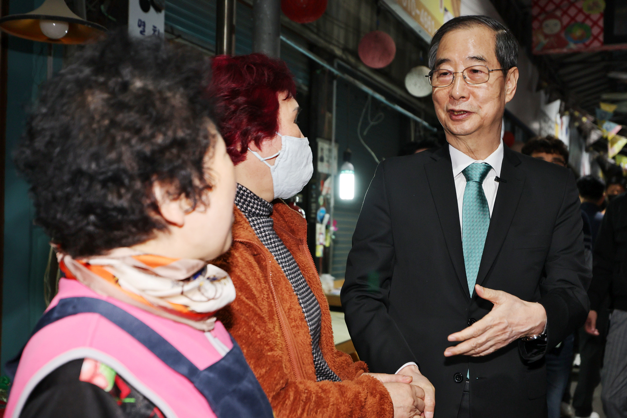 Former Prime Minister Han Duck-soo speaks with merchants at Daein Market in Gwangju, Friday. (Yonhap)