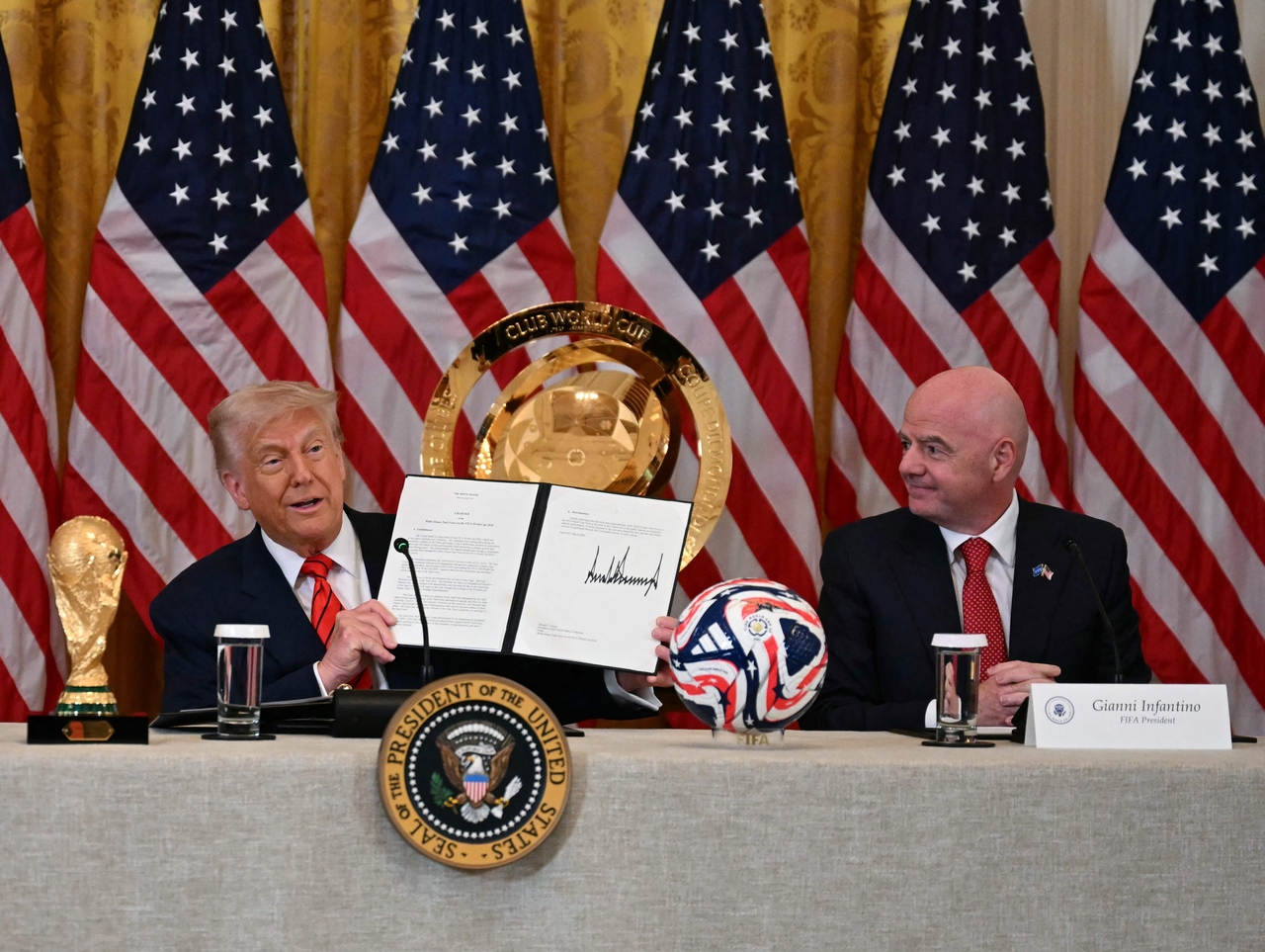 US President Donald Trump (left) holds up a document creating the "White House Task Force on the FIFA World Cup 2026" as FIFA president Gianni Infantino looks on , at the White house in Washington, Tuesday. (AFP-Yonhap)