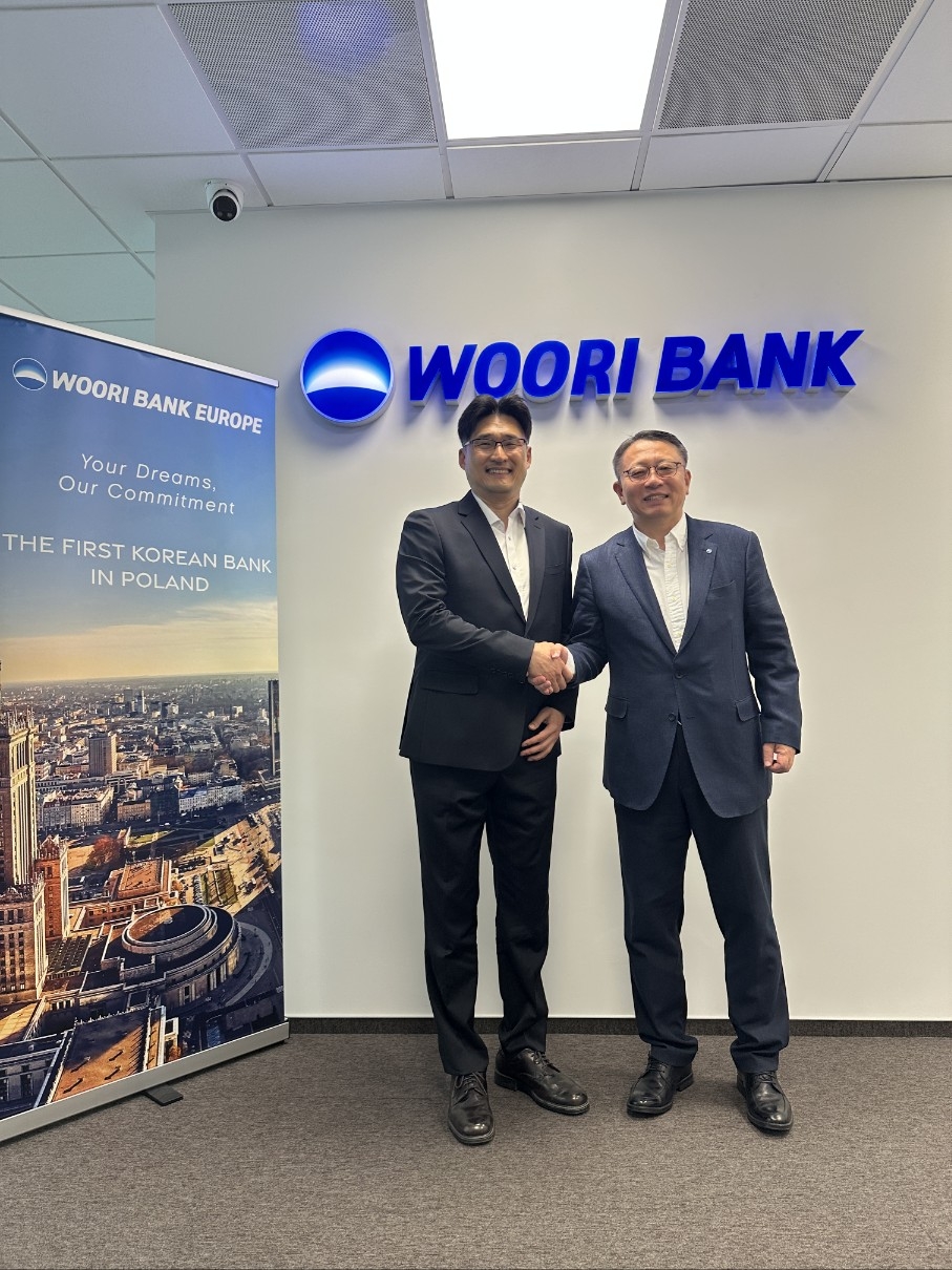 Woori Bank CEO Jung Jin-wan (right) shakes hands with Ahn Jeong-hwan, head of K-water’s Ukraine recovery task force, at the lender's Warsaw branch in Poland on Wednesday. (Woori Bank)
