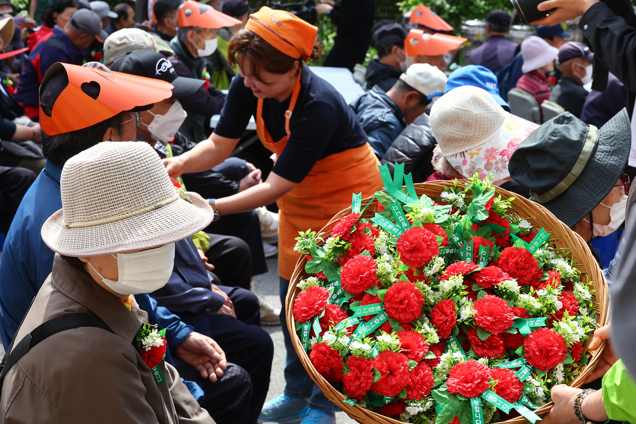 A volunteer pins a carnation on a senior citizen during a Parents’ Day event held in Dongdaemun-gu, Seoul on Thursday. (Yonhap)