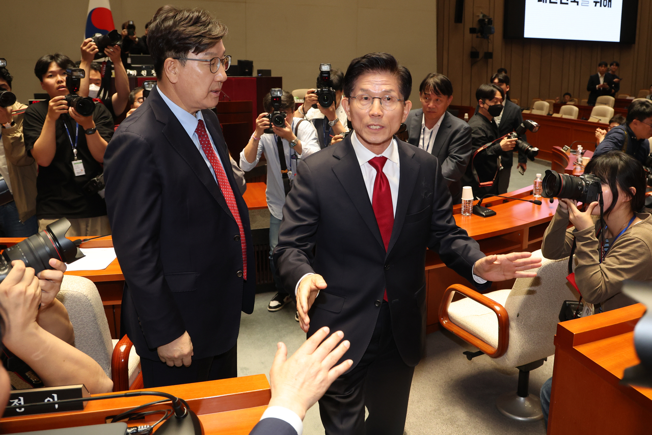 Kim Moon-soo (right), presidential candidate of the conservative People Power Party, walks out of a general meeting of PPP lawmakers at the National Assembly on Friday, after the PPP leadership pressures him to merge his candidacy with former Prime Minister Han Duck-soo. (Yonhap)