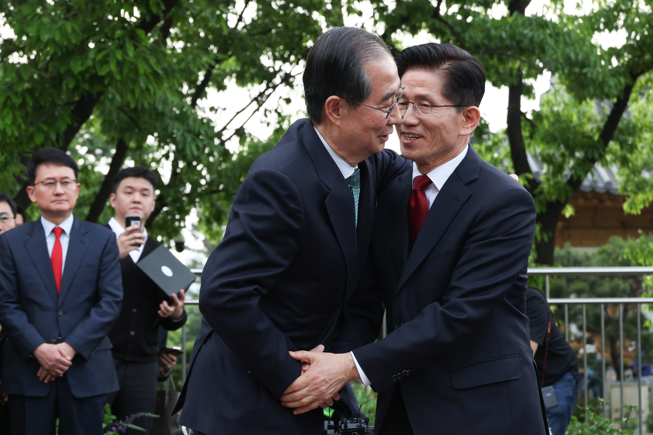 김문수(오른쪽) 국민의힘 대선후보와 한덕수(왼쪽) 무소속 대선 예비후보가 8일 서울 국회 사랑재에 위치한 커피숍에서 회동을 마친 후 포옹하고 있다. [연합]