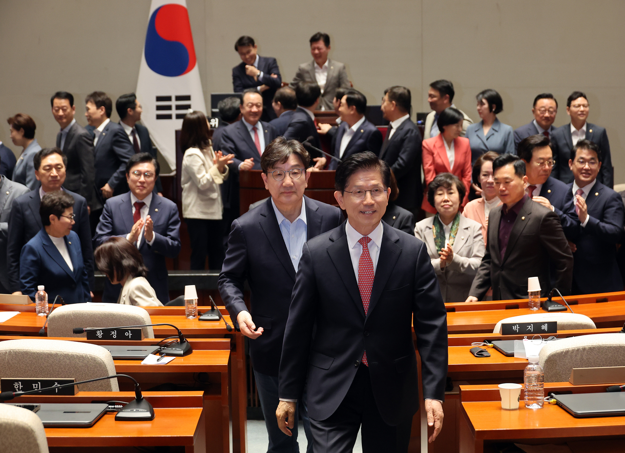 People Power Party presidential candidate Kim Moon-soo walks out with floor leader Rep. Kweon Seong-dong after taking a group photo with lawmakers during a general meeting at the National Assembly in Seoul on Sunday. Yonhap