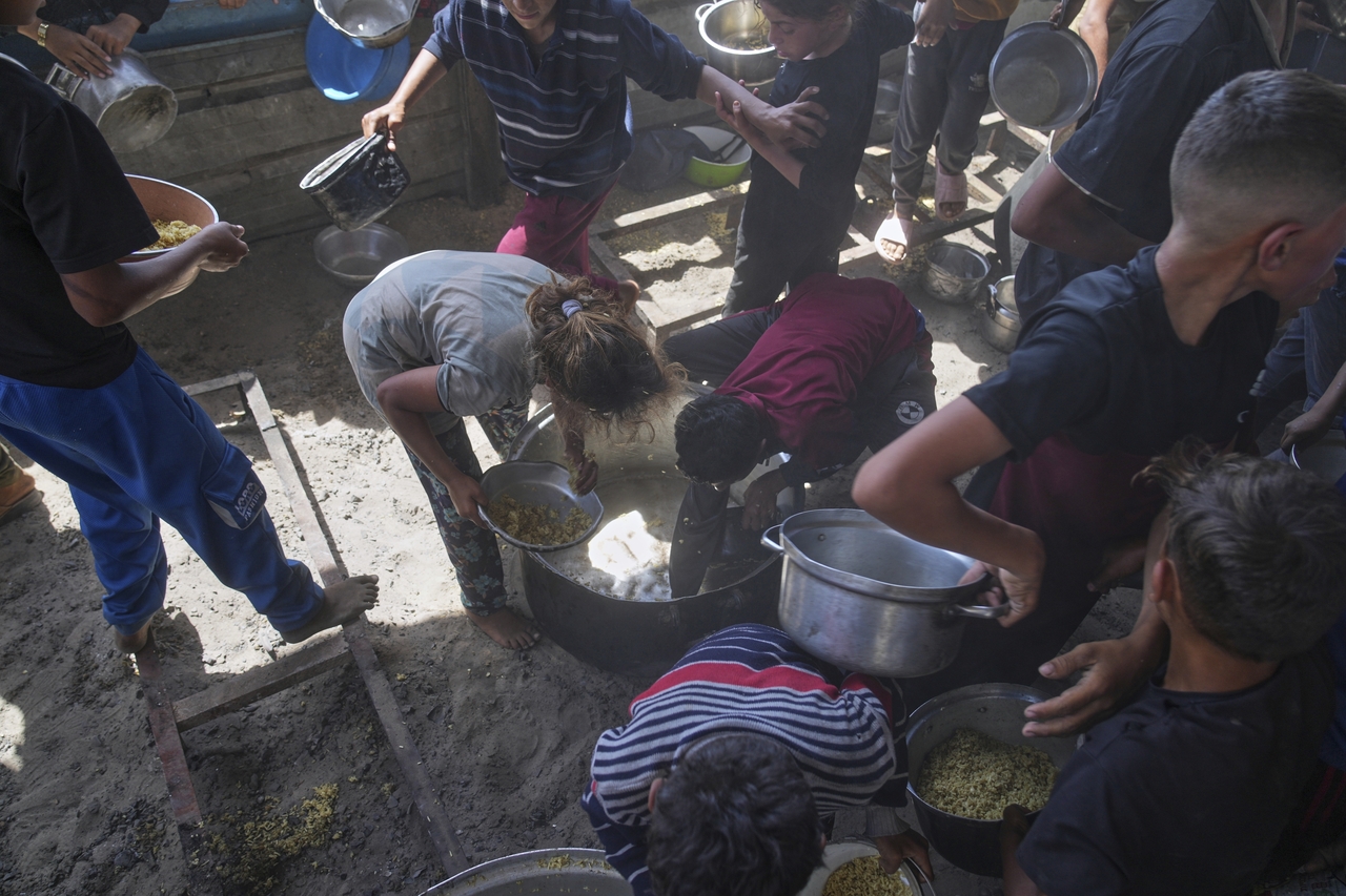 Palestinian children scrape a pot for food after all meals were distributed at a community kitchen in Khan Younis, Gaza Strip, Friday. (AP-Yonhap)