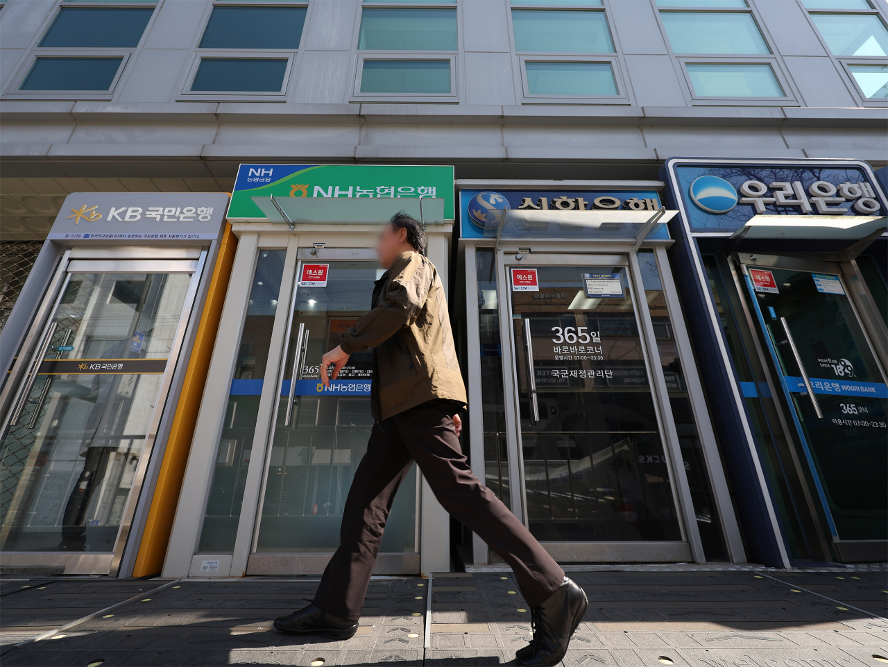 A man walks by ATMs of local banks installed on a street in Seoul. (Yonhap)