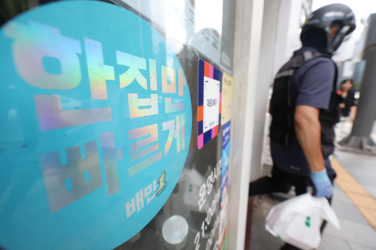 서울 시내 배달의민족 배민1 스티커 부착된 한 카페에 배달 기사가 주문한 음식을 들고 나서고 있다. [뉴시스]