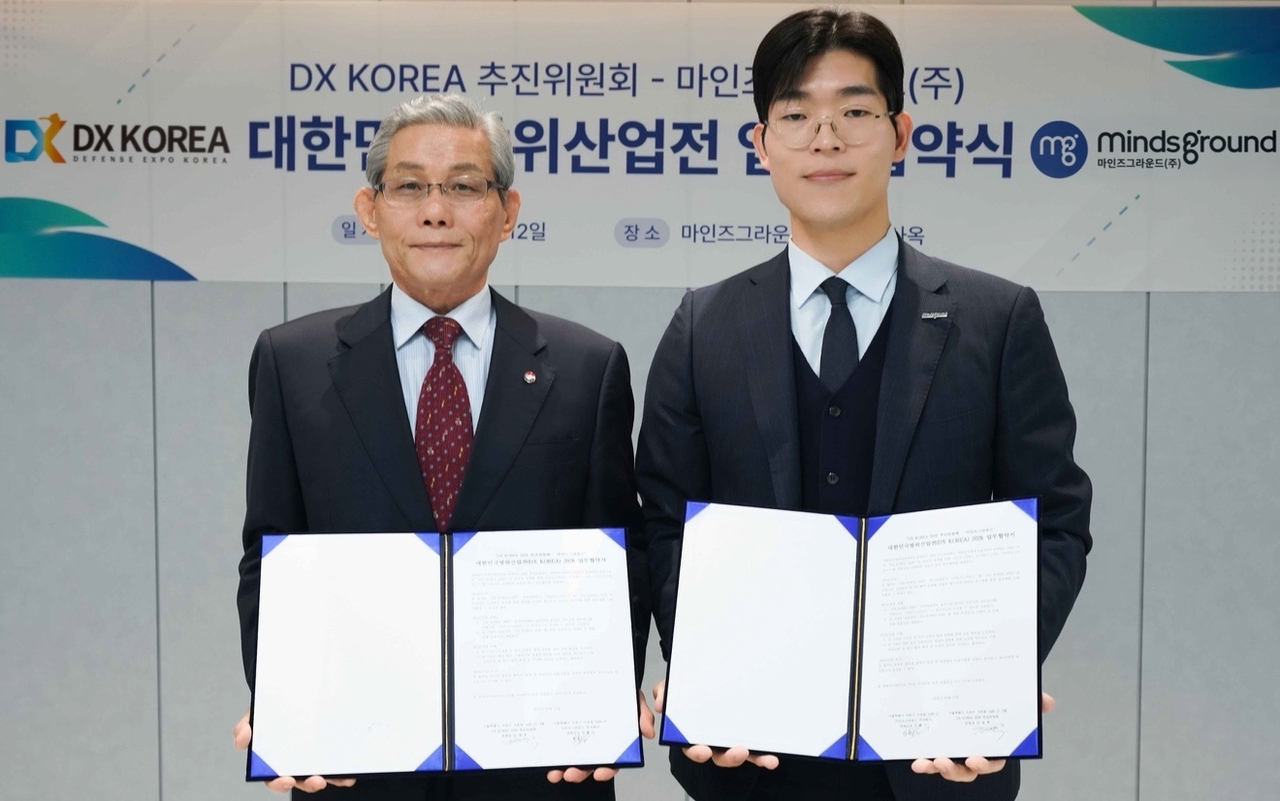 민환기(오른쪽) 마인즈그라운드 민환기 대표와 ‘DX KOREA 2026’ 추진위원회의 김영후 위원장이 12일 업무협약을 체결한 뒤 기념촬영하고 있다. [마인즈그라운드 제공]