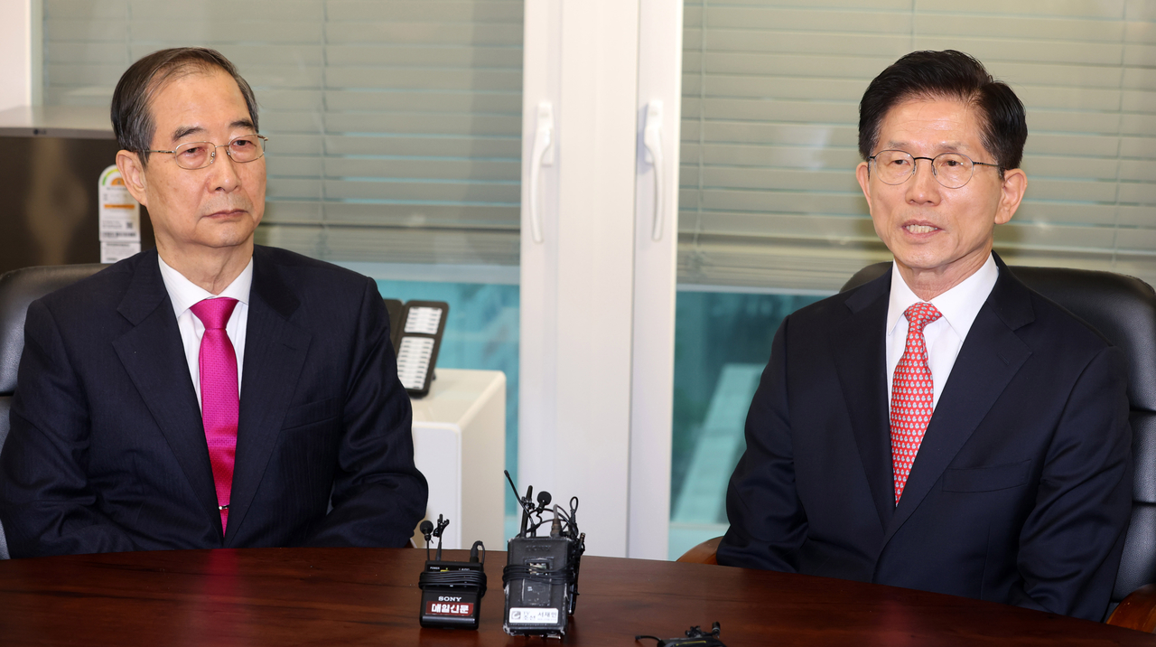 Former Prime Minister Han Duck-soo talks with People Power Party presidential candidate Kim Moon-soo during their meeting in Seoul on Sunday. (Yonhap)
