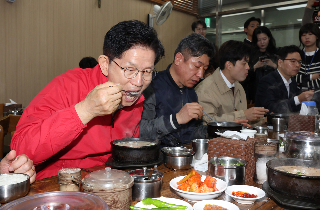People Power Party presidential candidate Kim Moon-soo eats sundae gukbap with vendors during a visit to Garak Market in Seoul’s Songpa-gu on Monday, the first day of the official campaign period for the 21st presidential election. (Yonhap)