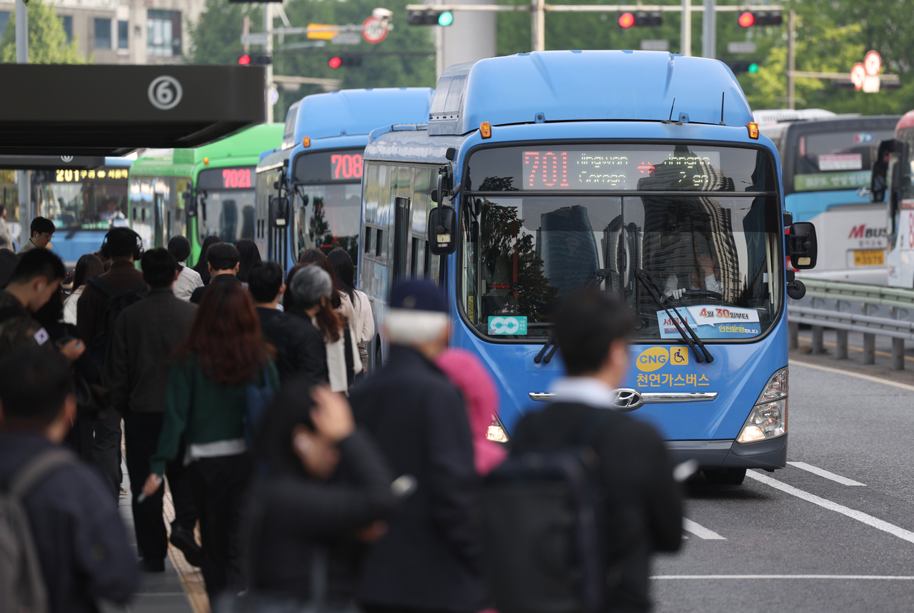 Commuters wait to board city buses at the busy bus transfer center outside Seoul Station last Thursday. (Newsis)
