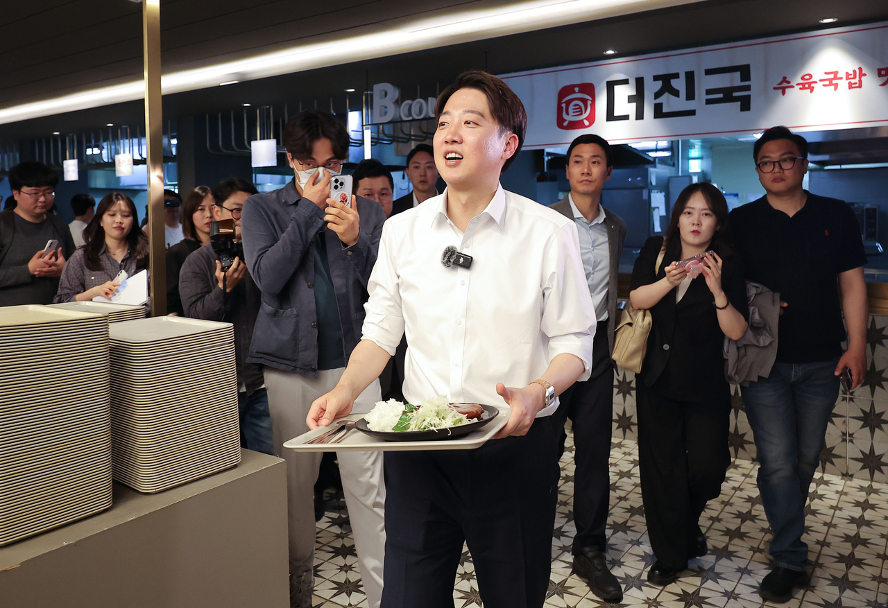 Lee Jun-seok, the presidential candidate of the minor conservative New Reform Party, carries a meal as he makes a stump stop at Kyungpook National University in the southeastern city of Daegu on Tuesday, ahead of the June 3 presidential election. (Yonhap)