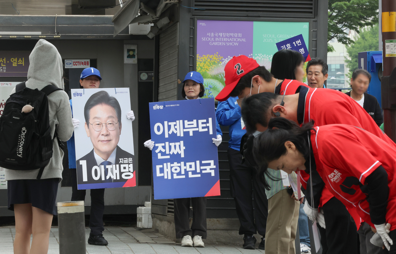 Supporters for Democratic Party of Korea candidate Lee Jae-myung (in blue shirts) and for People Power Party candidate Kim Moon-soo (in red shirts) campaign on a street in Seoul on Tuesday. (Yonhap)