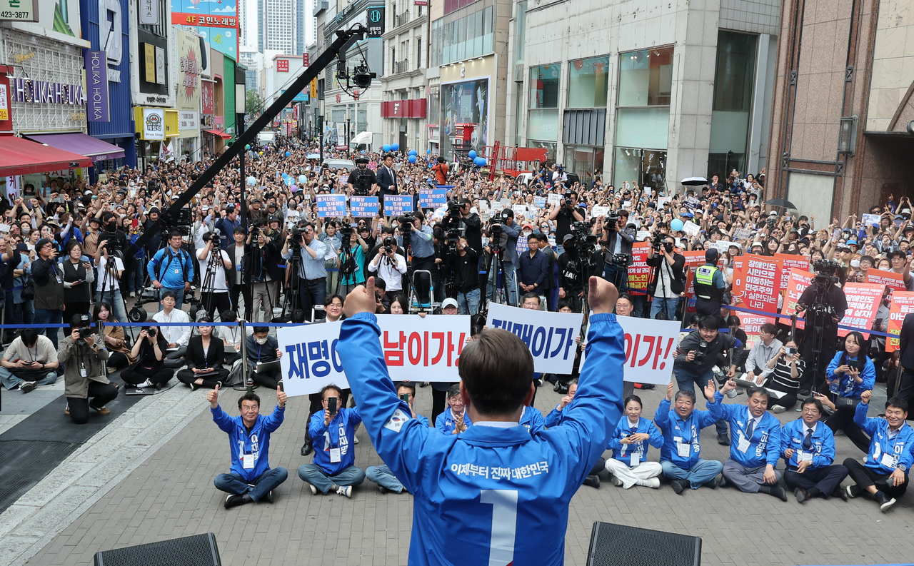 Lee Jae-myung raises both hands after delivering a speech on Dongseong-ro, a bustling street in the conservative stronghold of Daegu on Tuesday. (Joint Press Corps via Yonhap)