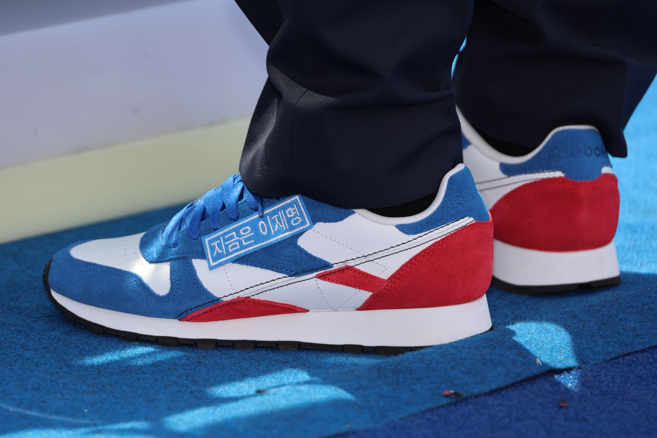 Lee Jae-myung, the Democratic Party of Korea's presidential candidate, wears blue and red Reebok sneakers with the slogan, "Lee Jae-myung, Now More Than Ever," during the party's launch event for the official campaign period in Seoul, Monday. (Newsis)