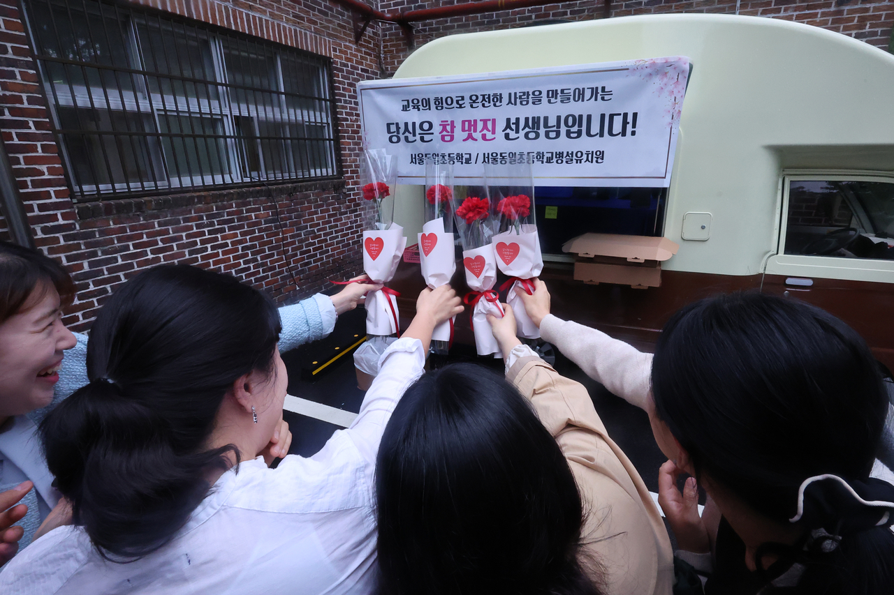 Teachers at Dongil Elementary School in Seoul take a commemorative photo of carnations they received Thursday. (Yonhap)