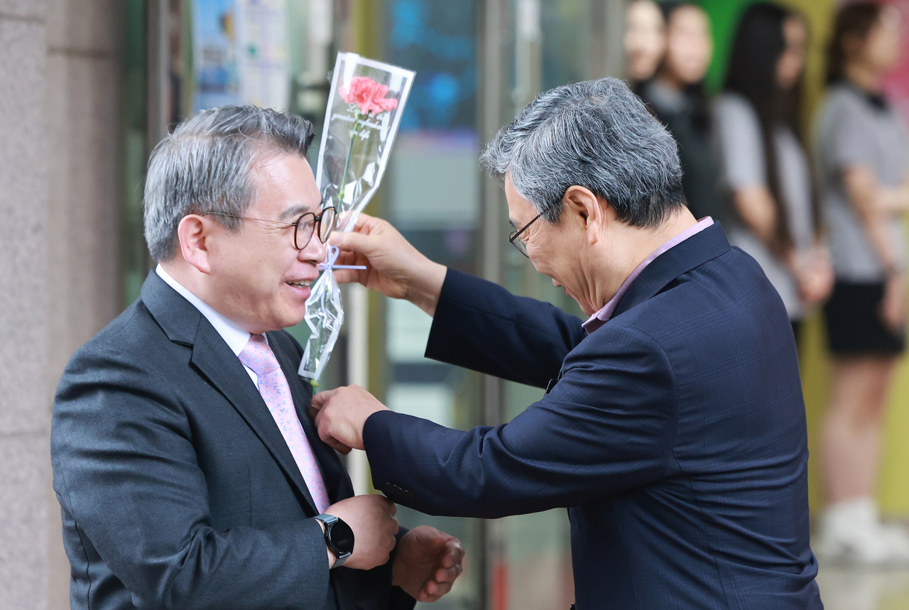 Chung Geun-sik, superintendent of the Seoul Metropolitan Office of Education, presents a carnation to principal Kang Sang-wook at Seoul Broadcasting High School in Seongdong-gu, Seoul, Thursday. (Yonhap)