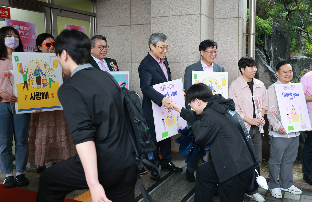 Chung Geun-sik (center), the Seoul Metropolitan Office of Education superintendent, and teachers at Seoul Broadcasting High School greet students with panels saying "I love you" and "Thank you" on Thursday. (Yonhap)