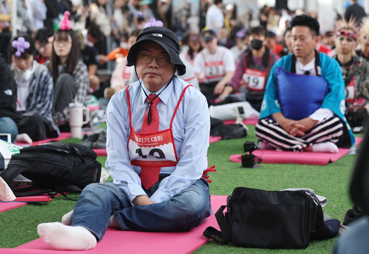 A South Korean office worker sits motionless during the 2025 Hangang Space Out Competition, held last Sunday at Banpo Hangang Park in Seoul, where participants aim to clear their minds and remain idle for over 90 minutes. (Newsis)
