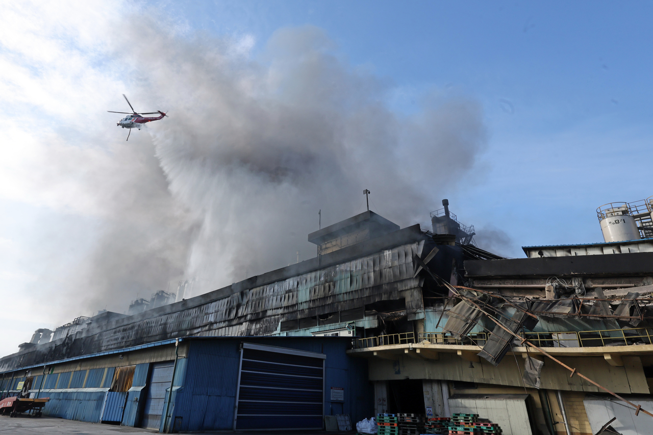 A firefighting helicopter circles the Kumho Tire plant in Gwangju on Sunday, working to extinguish the blaze that broke out Saturday morning. (Yonhap)