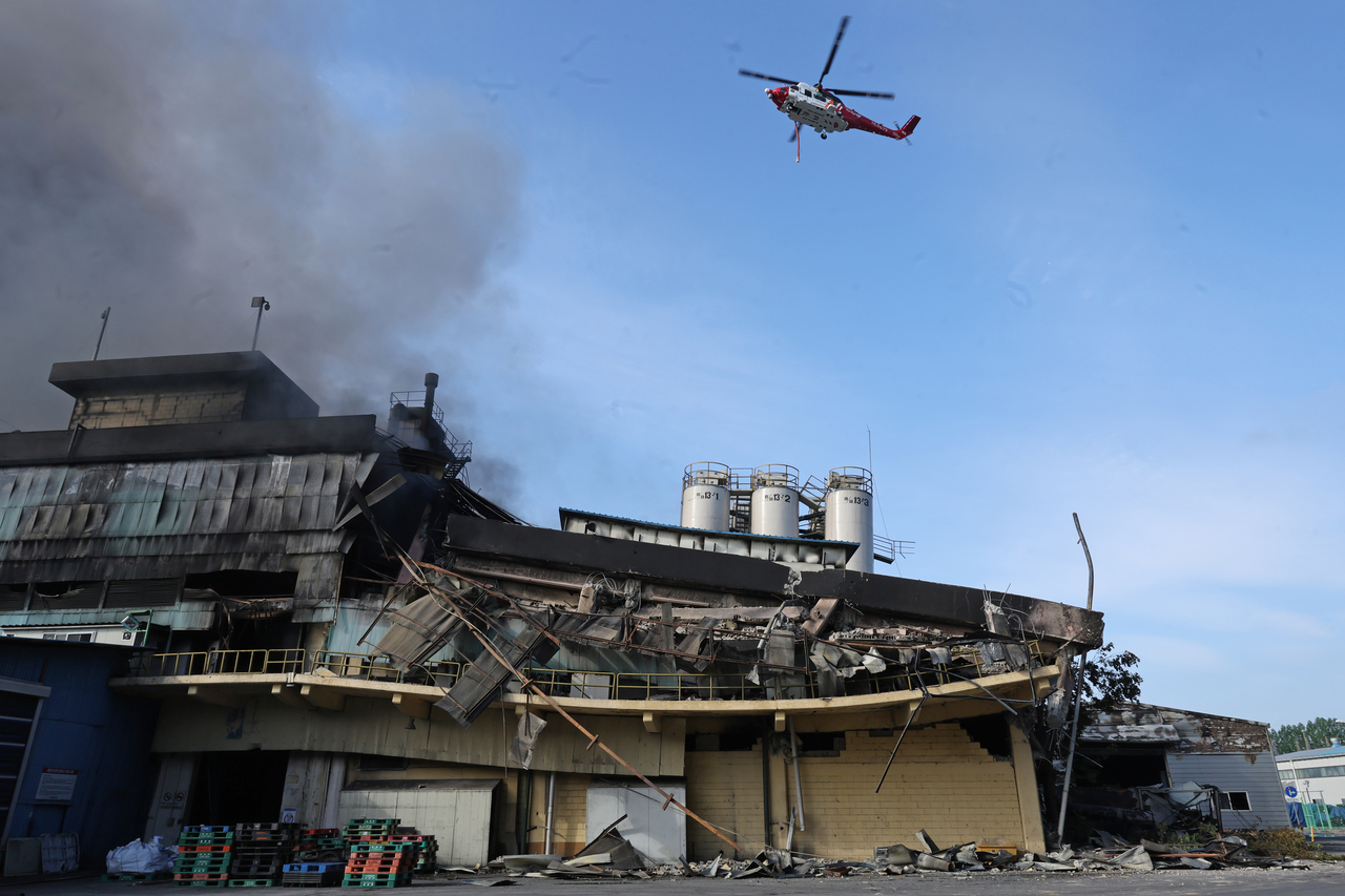 A firefighting helicopter flies over Kumho Tire plant in Gwangju on Sunday, following a fire that broke out on Saturday. (Yonhap)