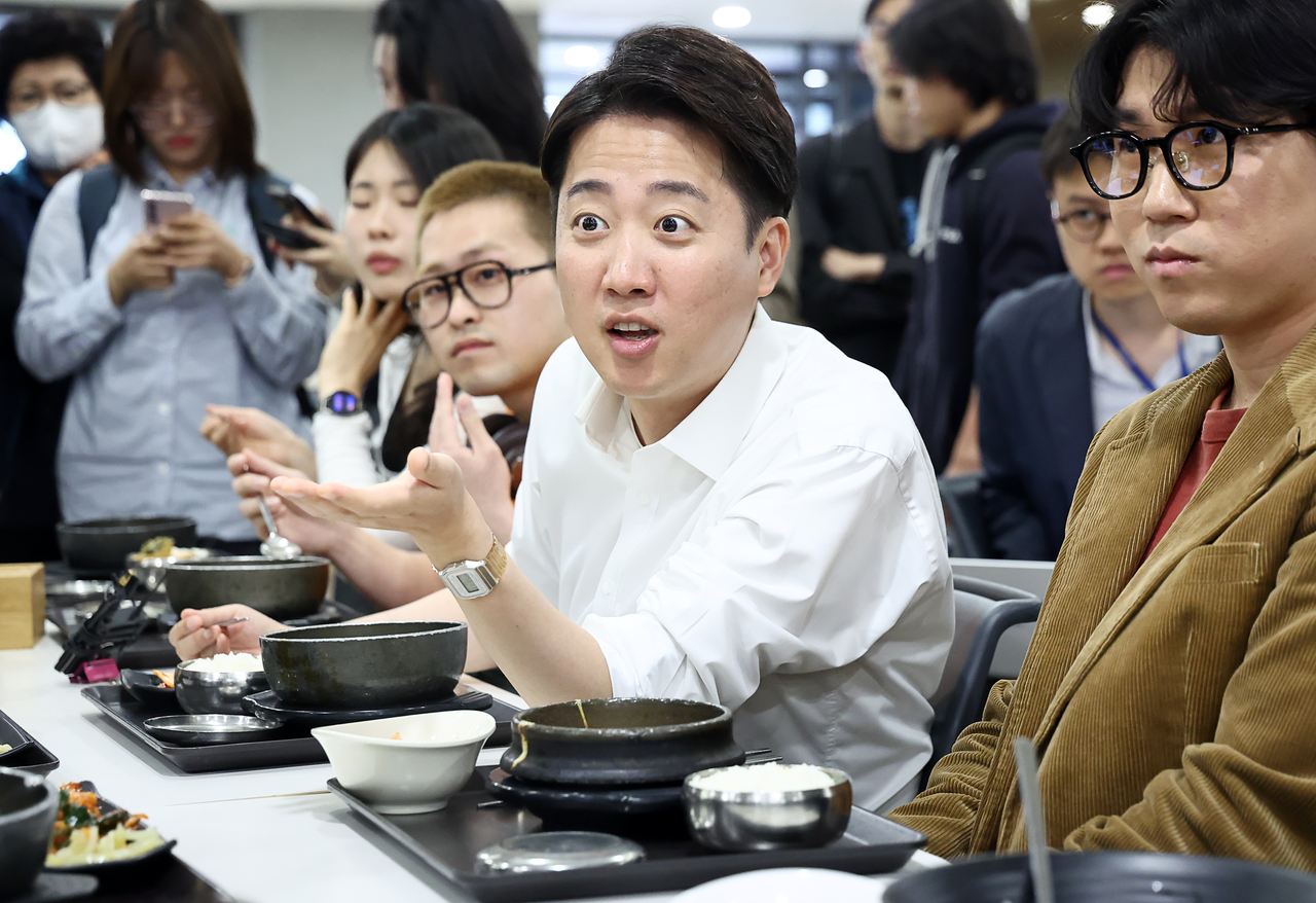Lee (center) speaks with students over lunch during a visit to Yonsei University in Seoul on May 12, as part of his campaign efforts to appeal to younger voters. (Yonhap)