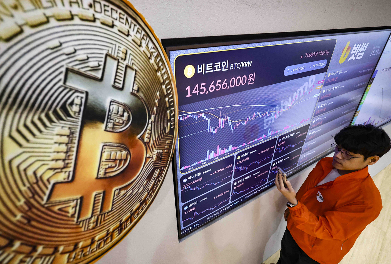 A man checks the Bitcoin price on an electronic display at Bithumb’s customer lounge in Gangnam-gu, Seoul, on May 12. (Newsis)