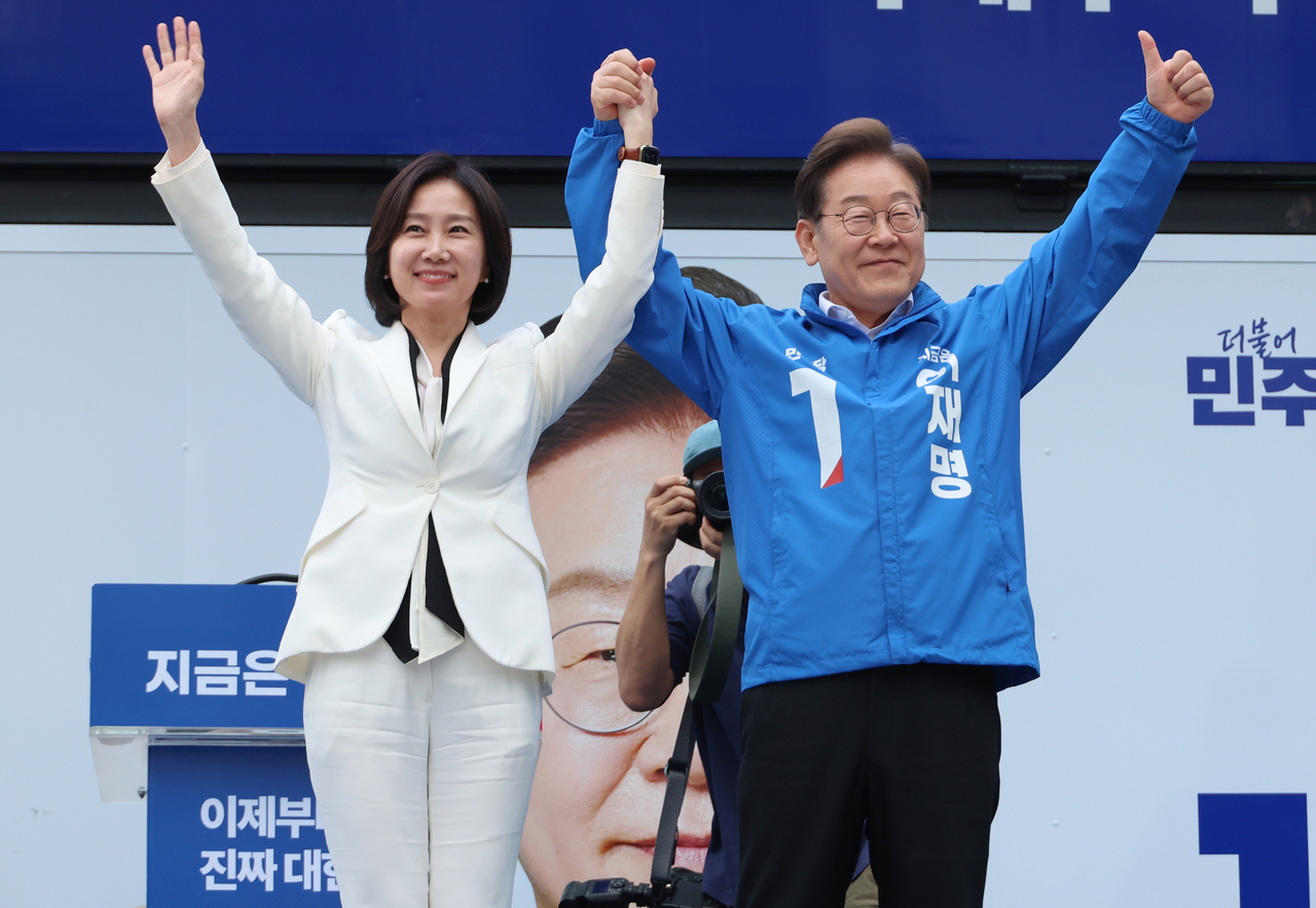 Democratic Party presidential candidate Lee Jae-myung poses hand in hand with Her Eun-a, former leader of the New Reform Party, during a campaign rally at Times Square in Yeongdeungpo-gu, Seoul, on Monday. (Yonhap)