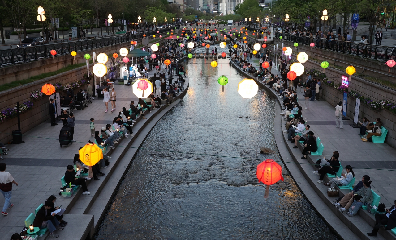 Seoul residents take part in a riverside reading event at the Cheonggyecheon on April 23, coinciding with the launch of the city’s outdoor library program for World Book and Copyright Day. The road on both sides of the stream have been closed to vehicles during designated hours. (Newsis)