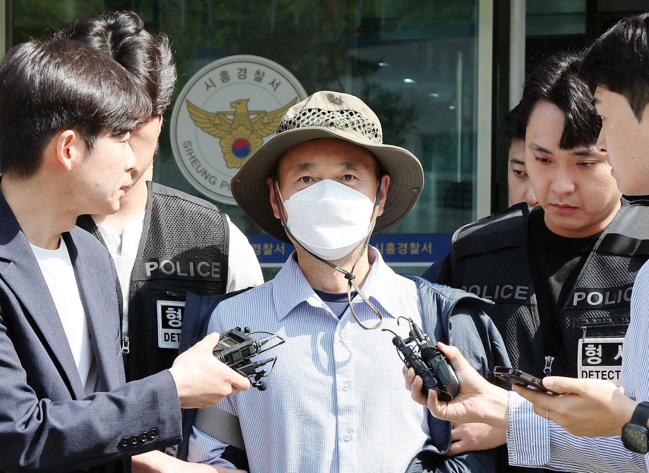 Cha Cheol-nam (center), a Chinese national of Korean ethnicity accused of killing two people and injuring two others, appears outside Siheung Police Station in Siheung, southwest of Seoul, on Wed. (Yonhap)