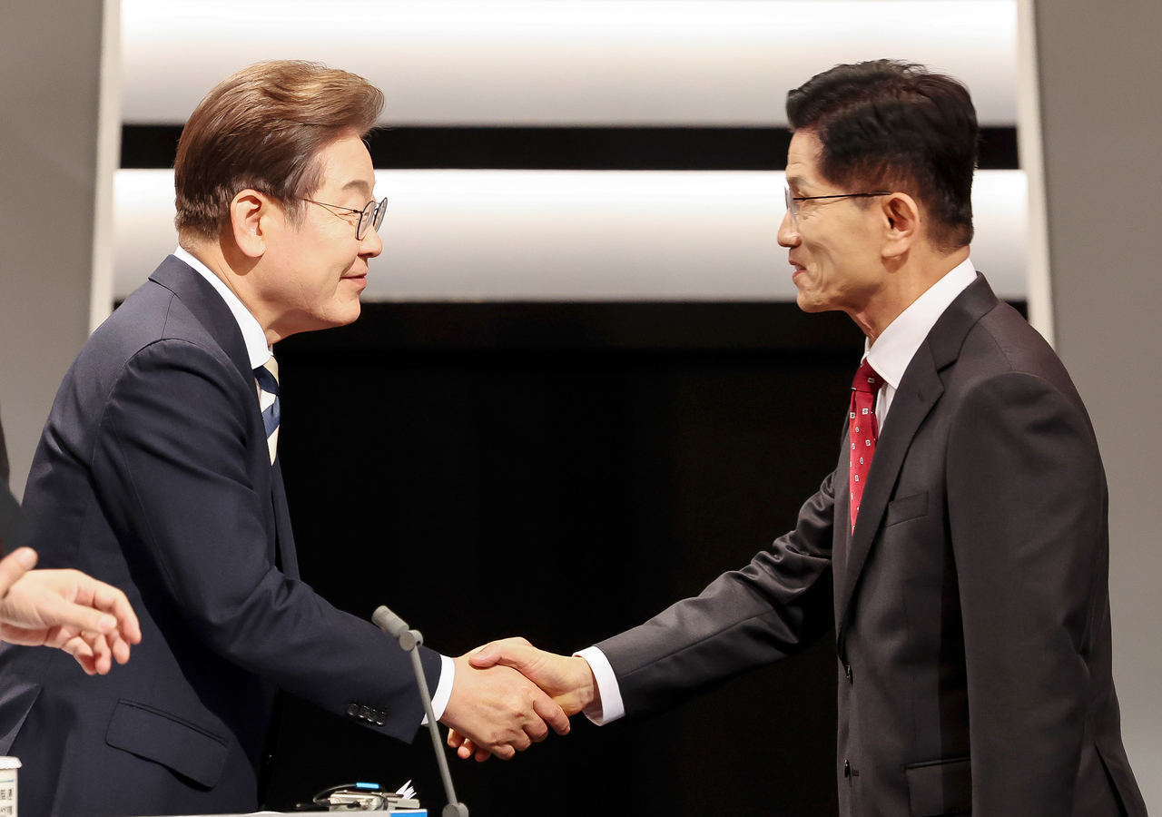 Democratic Party of Korea presidential candidate Lee Jae-myung, left, and People Power Party presidential candidate Kim Moon-soo shake hands before entering a televised debate filmed at the KBS Studio in western Seoul on Friday. Yonhap