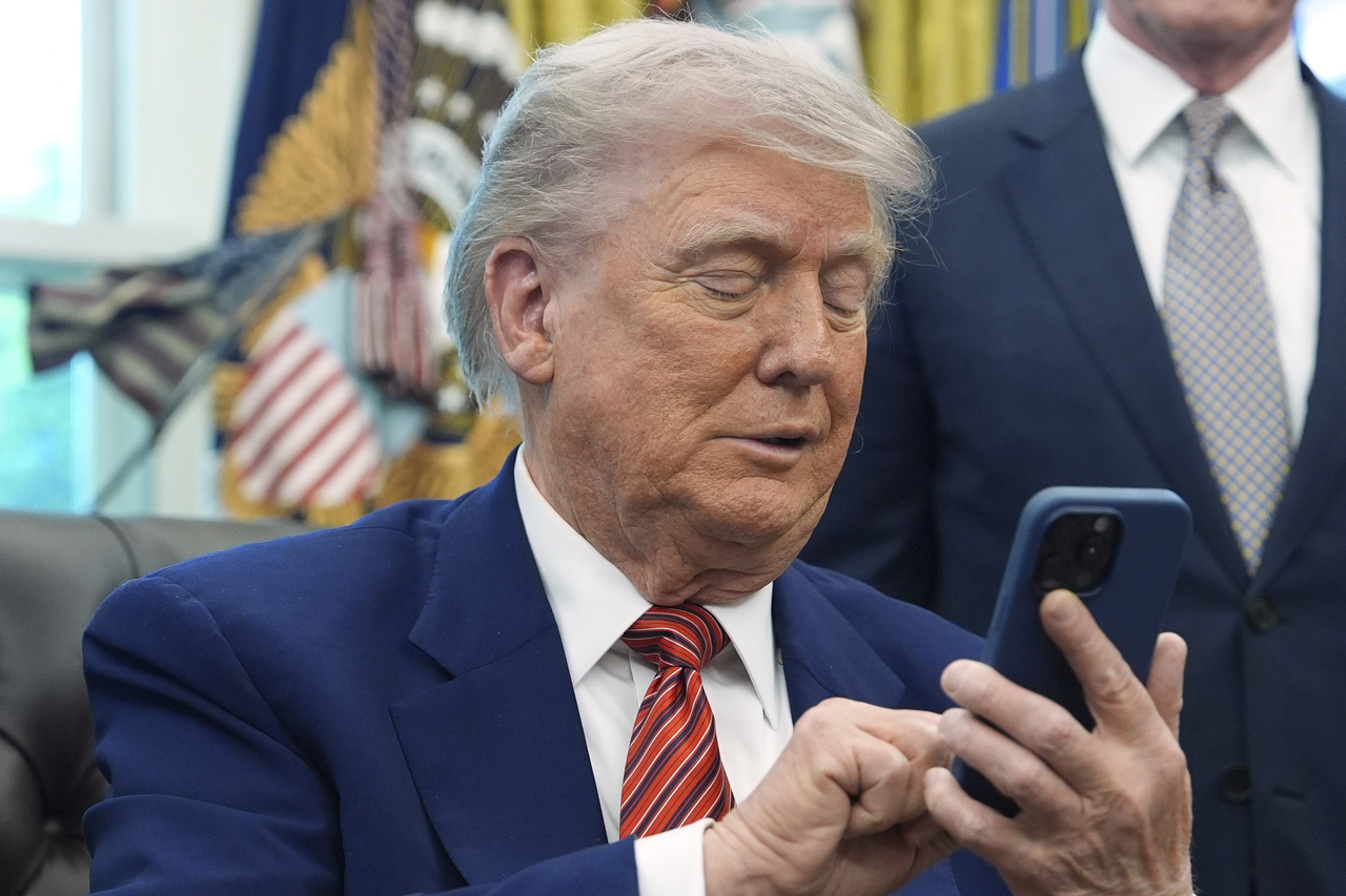 US President Donald Trump silences his mobile phone, which rang two times as he was speaking to reporters after signing executive orders regarding nuclear energy in the Oval Office of the White House, Friday, in Washington. (AP-Yonhap)