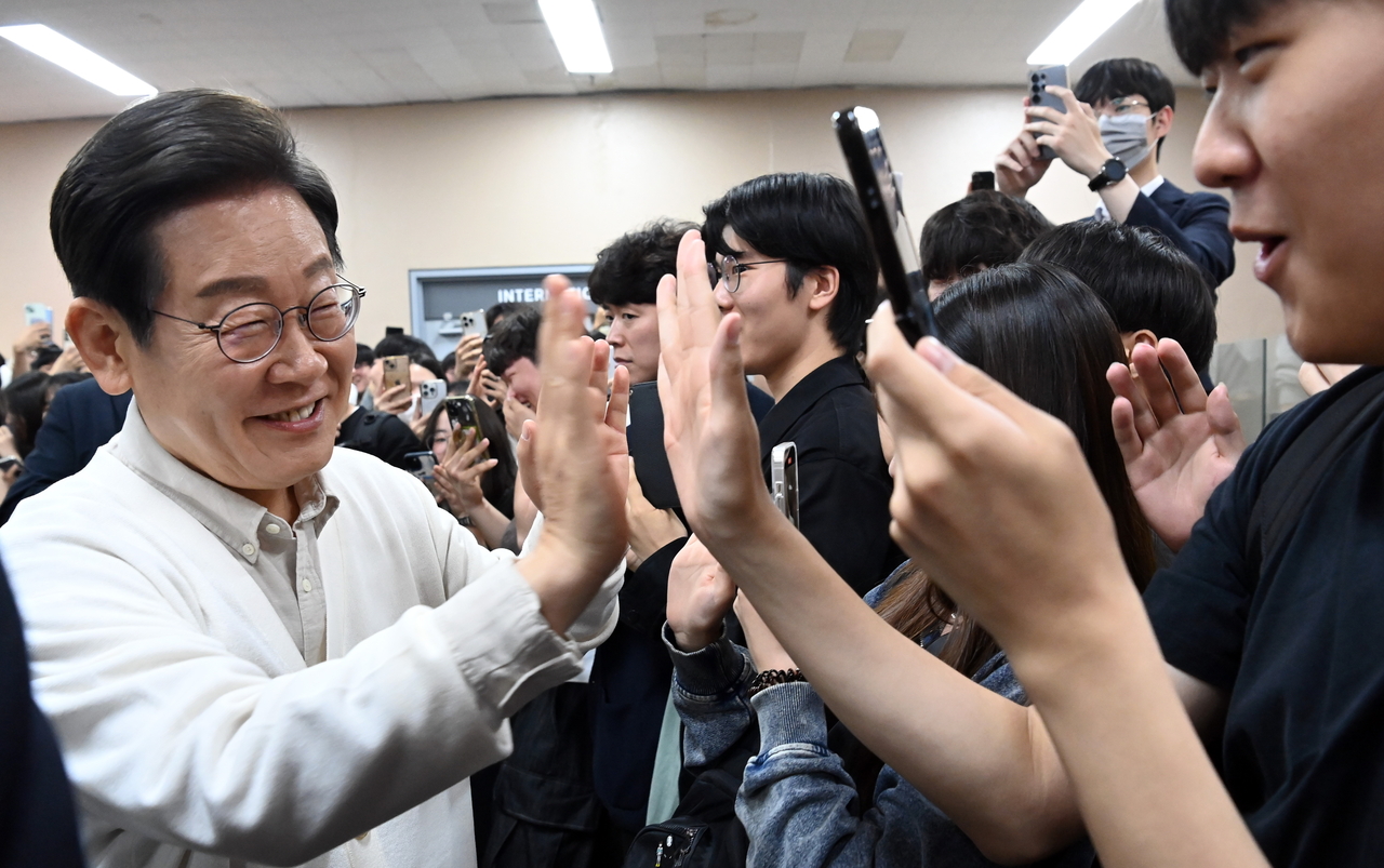 Democratic Party of Korea presidential candidate Rep. Lee Jae-myung (left) high-fives college students after discussing policies related to young people during a campaign stop at Ajou University in Suwon, Gyeonggi Province, Monday. (Im Se-jun/The Korea Herald)
